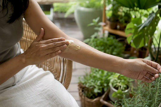 Hands applying mango butter on skin outdoors