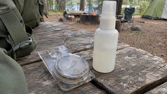 Clouded plastic compass beside a repellent bottle